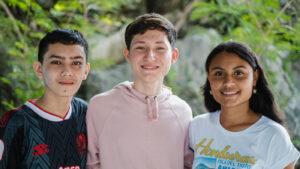 Tres jóvenes sonriendo en la naturaleza.