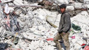 Joven camina entre escombros tras terremoto en Siria.