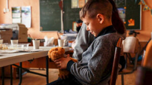 Niño ucraniano juega con oso de peluche.