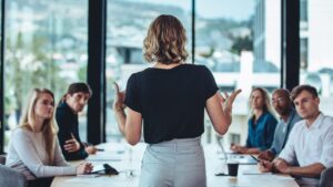 Mujer dando una charla a varias personas en una sala de reunión