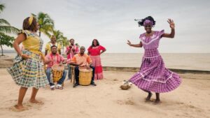 Mujeres celebrando su identidad cultural en la playa con trajes típicos