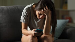 Niña en el celular preocupada por el ciberacoso
