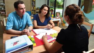 Maestra hablándole a padres de familia sobre la conducta disruptiva de sus hijos