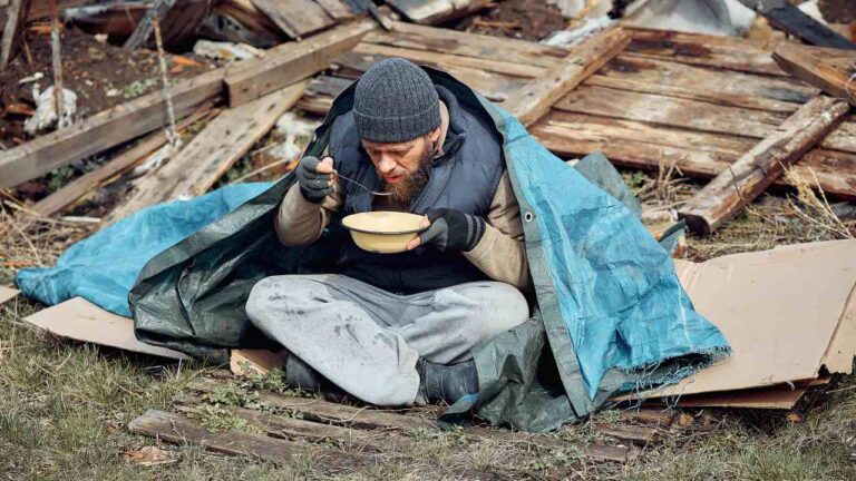 Hombre comiendo en la calle por las causas de la pobreza