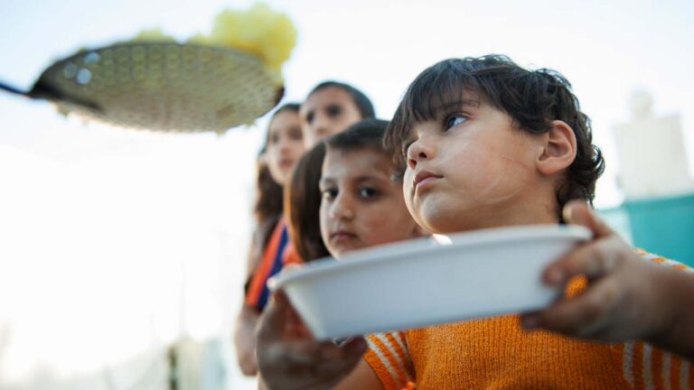 Niños recibiendo un plato de comida tras ser afectados por la desnutrición infantil