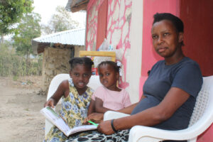 dos niñas con un libro junto a su mamá