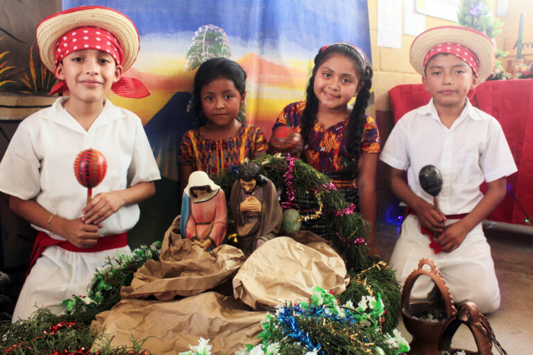 Niños guatemaltecos junto a un nacimiento, celebrando las tradiciones navideñas y la fe cristiana.
