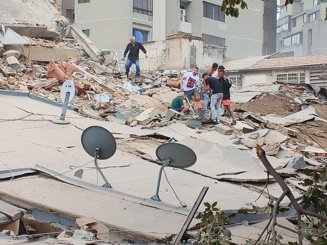 Personas observan los daños de un edificio colapsado tras el terremoto en Venezuela.
